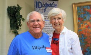 An elderly volunteer couple smile for the camera while serving food to volunteers in the hospitality room at an Identification Clinic