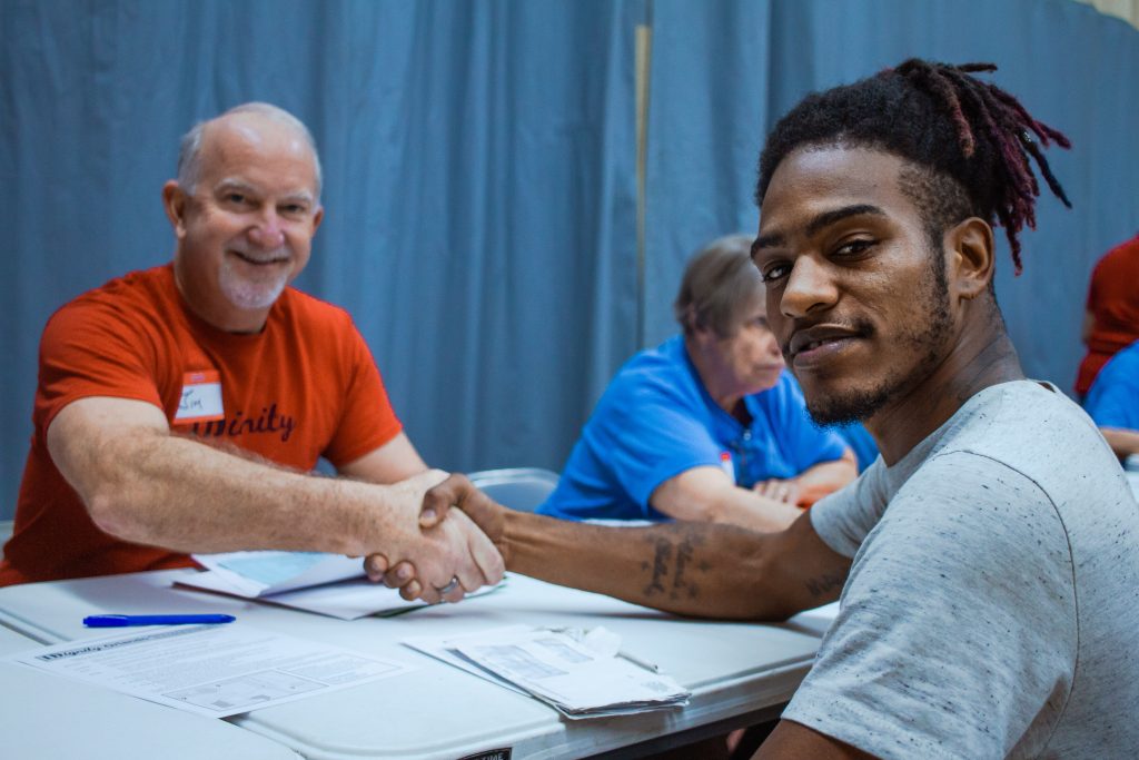 An IDignity client shares a friendly hand shake with the volunteer that helped him.