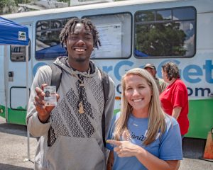 An IDignity volunteer representing Fast Signs poses with a client and his new Florida ID.