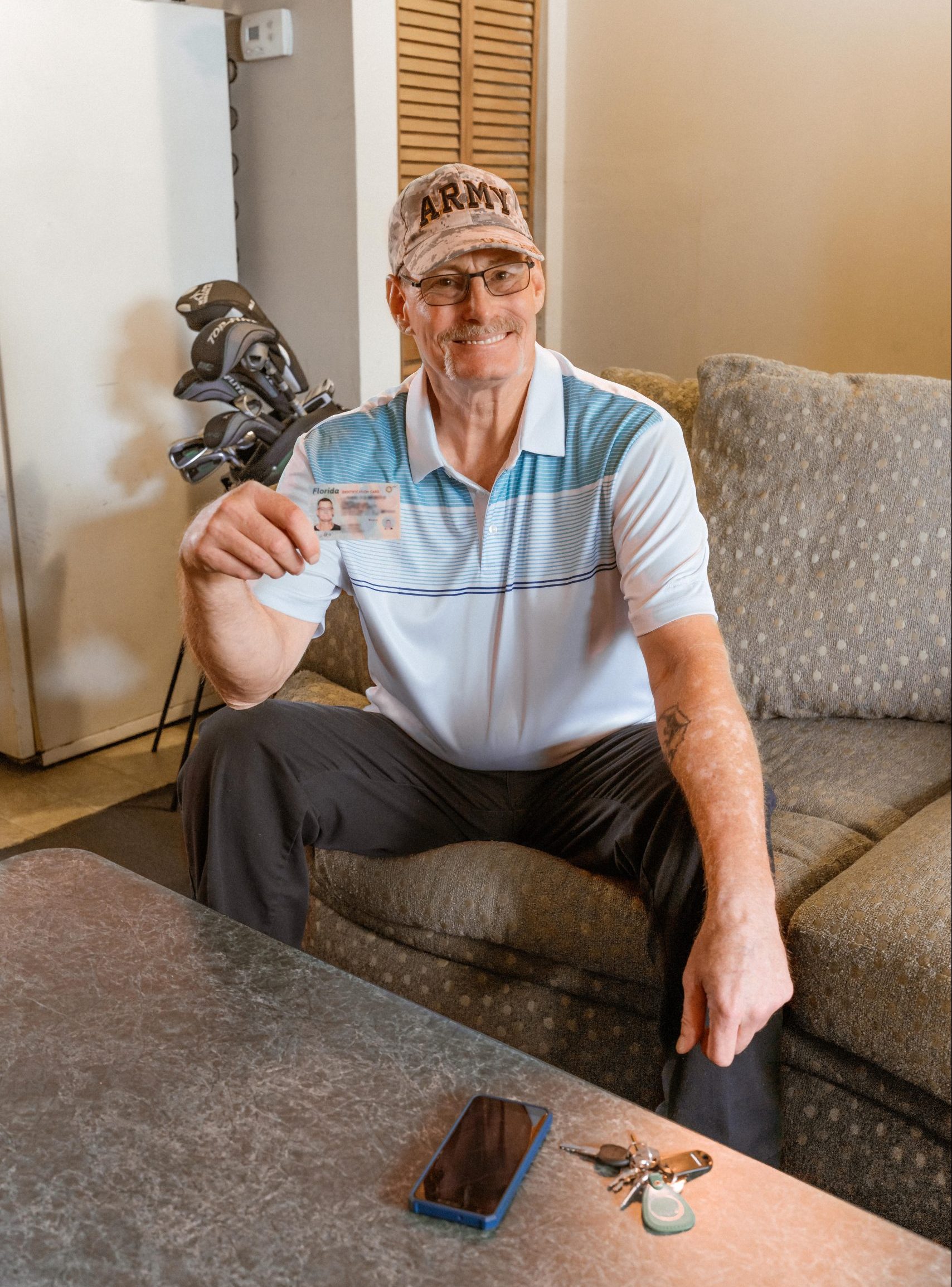 IDignity client Chris, on his couch in his apartment with the ID that made it possible.